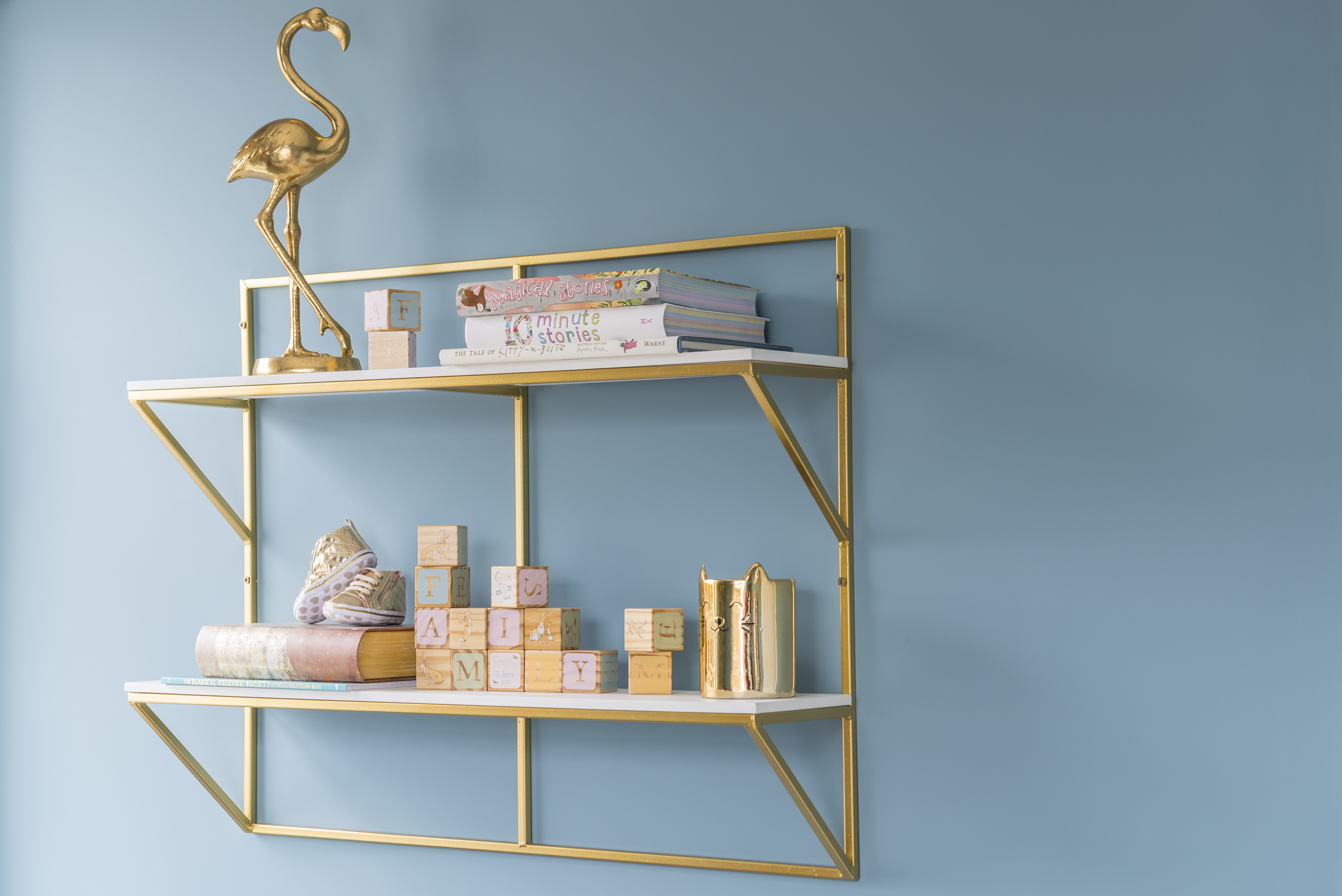 White and gold shelving with children's decorative items, gold flamingo and books