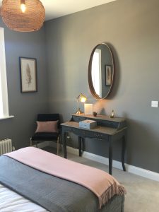 Dark grey vintage vanity table with statement mirror, small black chair and pink cushion