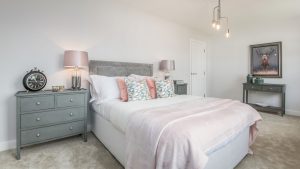 Grey bed with duck egg cabinet, pink lamp, pink throw, pink and blue cushions, decorative art and lamps