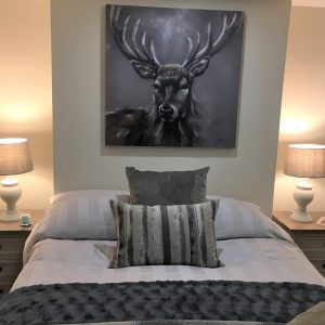 Bedroom with statement stag art on wall, cushions and lamps